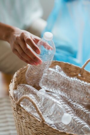 person putting empty plastic bottles in a basket